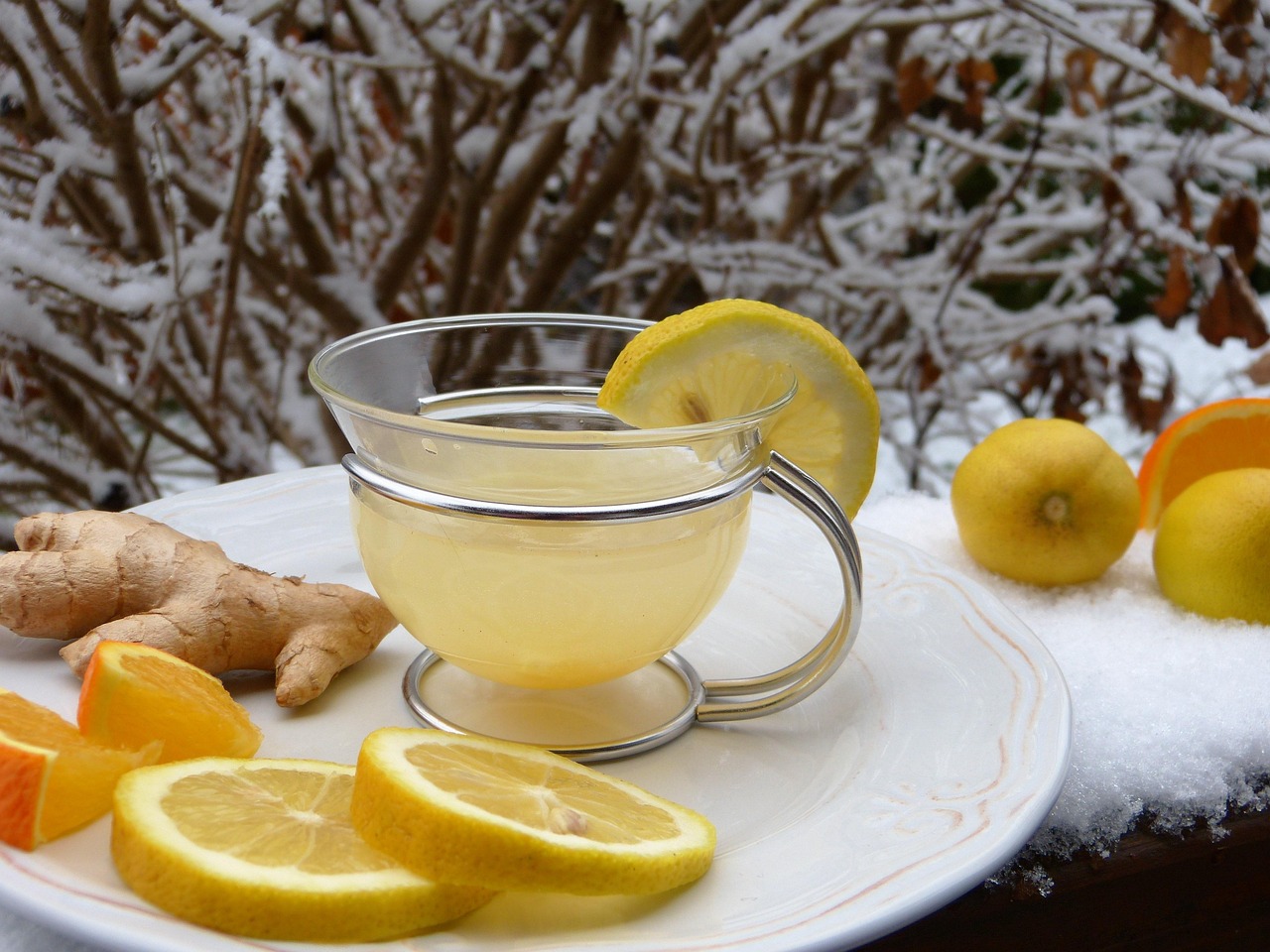 Bicchiere di acqua con limone e zenzero, ingredienti per un drink dimagrante.