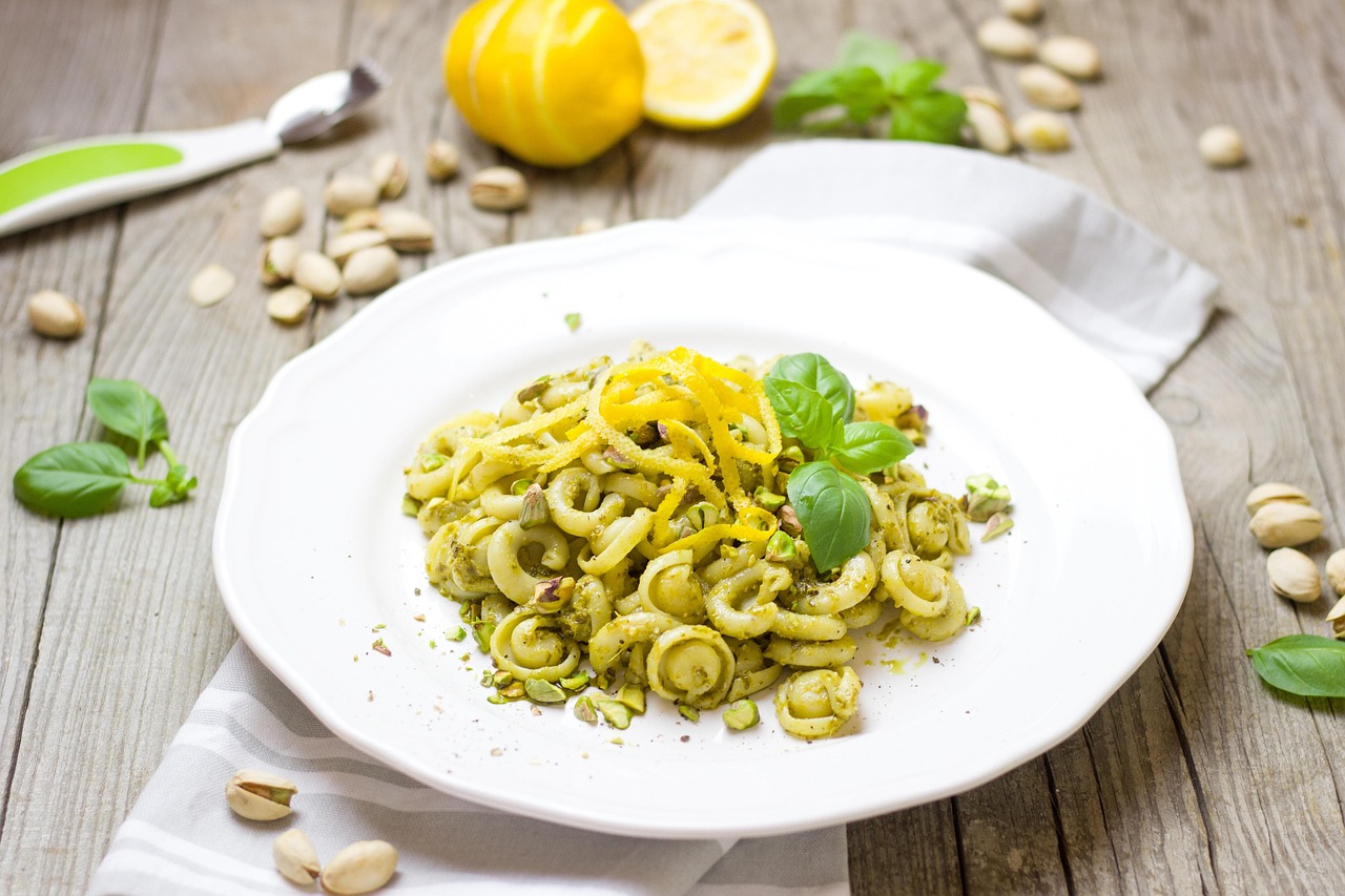 Pasta al pistacchio e speck servita in un piatto, guarnita con pistacchi tritati.
